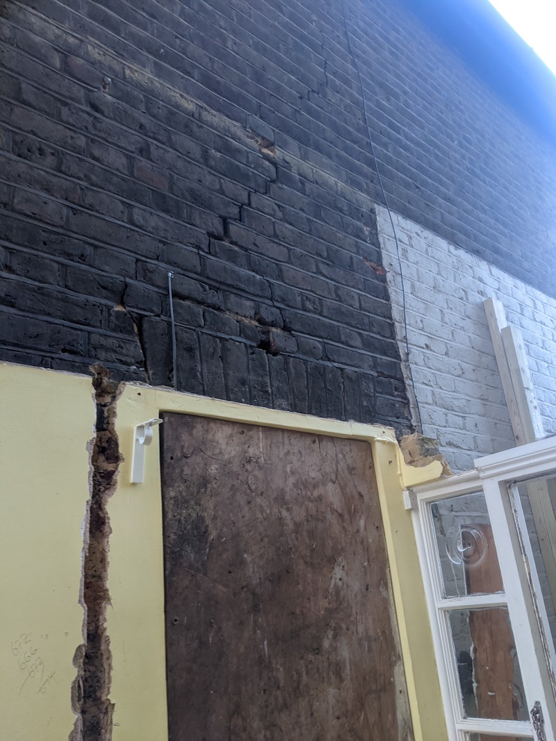 A big crack in a brick wall over a doorway